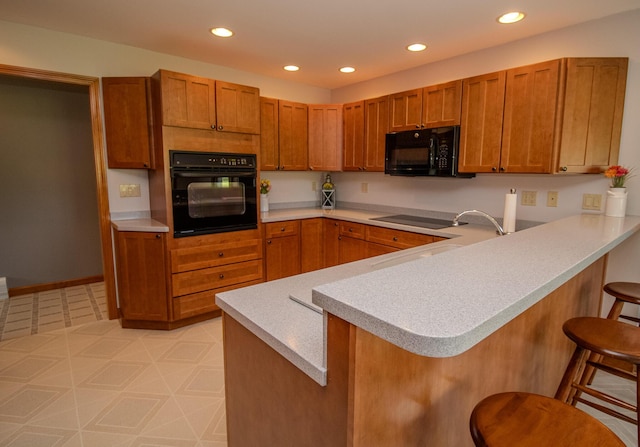 32 Ridge Rd, Marshfield, ME 04654 - kitchen featuring black appliances, a breakfast bar, a peninsula, light countertops, and brown cabinets