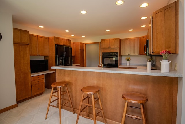 32 Ridge Rd, Marshfield, ME 04654 - kitchen with black appliances, a peninsula, recessed lighting, brown cabinetry, and light flooring