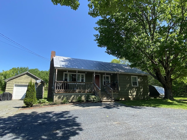 260 River Rd, Anson, ME 04958 - view of front facade featuring covered porch, a chimney, gravel driveway, a detached garage, and an outdoor structure