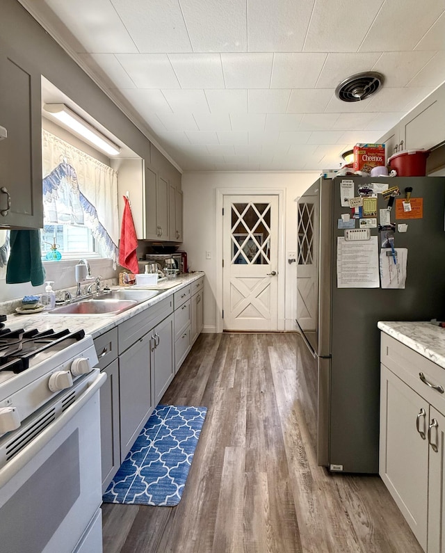 755 Main St, Calais, ME 04619 - kitchen featuring freestanding refrigerator, white range with gas cooktop, wood finished floors, gray cabinetry, and light countertops
