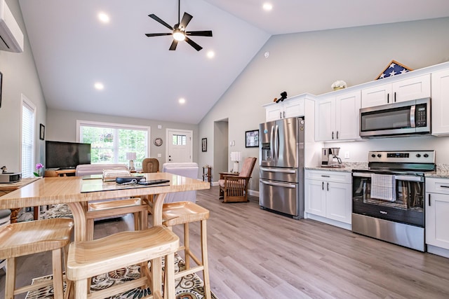 144 Ridley Rd, Sanford, ME 04073 - kitchen featuring appliances with stainless steel finishes, a wall mounted AC, high vaulted ceiling, white cabinetry, and ceiling fan