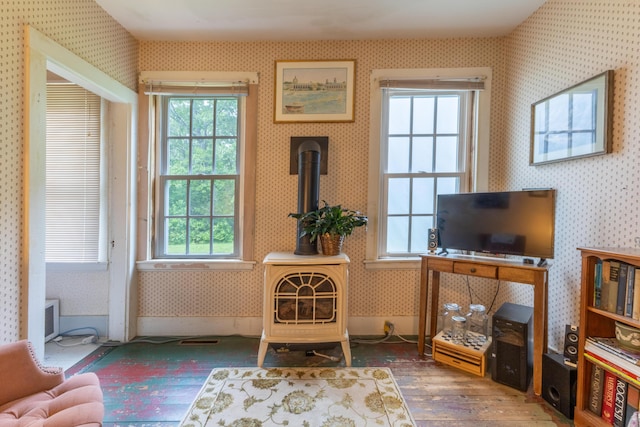 6 Paddy Ln, Franklin, ME 04634 - sitting room with wallpapered walls, a wood stove, wood-type flooring, and healthy amount of natural light