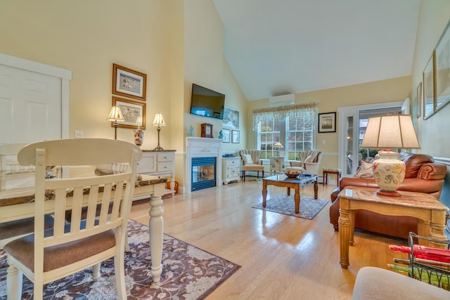86 Farragut Way Unit 86, Kennebunk, ME 04043 - living room featuring high vaulted ceiling, a wall mounted AC, light wood-type flooring, and a glass covered fireplace