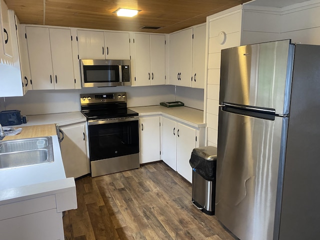 23 Page Rd, Enfield, ME 04493 - kitchen with appliances with stainless steel finishes, wood ceiling, light countertops, dark wood-type flooring, and white cabinets
