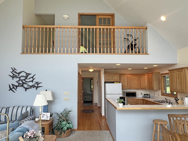 31 Deer Run, Lamoine, ME 04605 - kitchen featuring stainless steel microwave, freestanding refrigerator, high vaulted ceiling, a kitchen breakfast bar, and light wood-type flooring