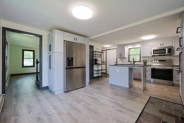 9 Jean St, Kittery, ME 03904 - kitchen featuring appliances with stainless steel finishes, light wood-type flooring, decorative backsplash, and dark countertops