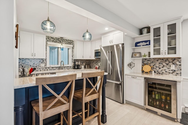 135 Ocean Ave Unit 15, Kennebunkport, ME 04046 - kitchen with stainless steel appliances, beverage cooler, tasteful backsplash, a breakfast bar area, and white cabinetry