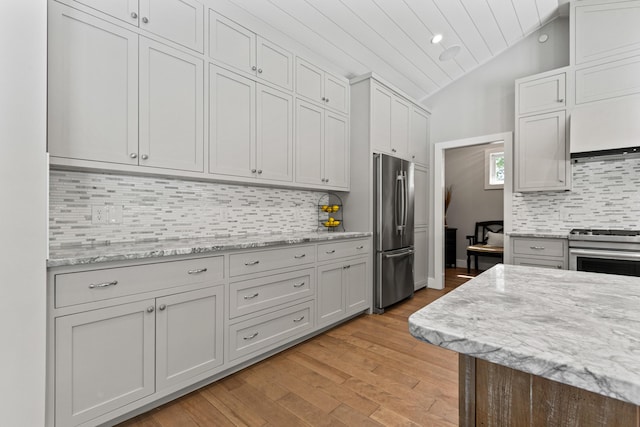 56 Ledgewood Dr, Falmouth, ME 04105 - kitchen with appliances with stainless steel finishes, light wood-type flooring, decorative backsplash, lofted ceiling, and light stone counters