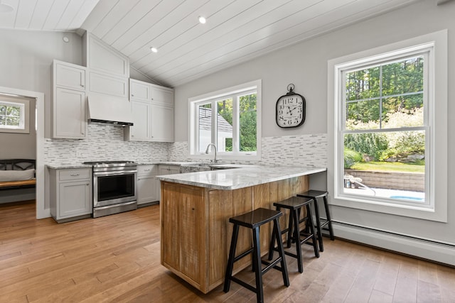 56 Ledgewood Dr, Falmouth, ME 04105 - kitchen with stainless steel gas stove, a peninsula, lofted ceiling, baseboard heating, and light wood-style floors
