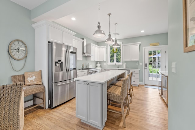 18 Frontier Way Unit 162, Arundel, ME 04046 - kitchen featuring stainless steel fridge, wall chimney exhaust hood, a center island, a breakfast bar, and white cabinetry