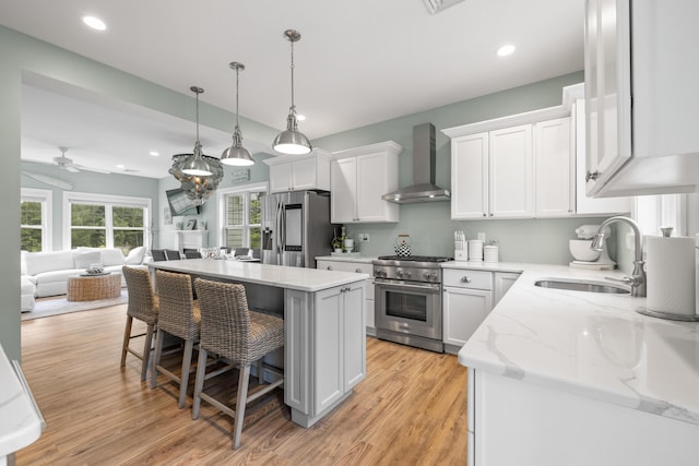 18 Frontier Way Unit 162, Arundel, ME 04046 - kitchen with wall chimney exhaust hood, appliances with stainless steel finishes, white cabinetry, a kitchen breakfast bar, and a center island