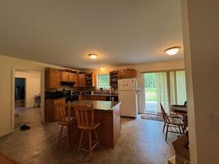 408 Chopps Cross Rd, Woolwich, ME 04579 - kitchen with freestanding refrigerator, a kitchen island, a breakfast bar area, and brown cabinetry