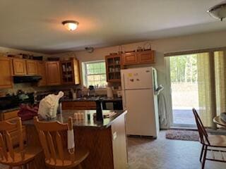 408 Chopps Cross Rd, Woolwich, ME 04579 - kitchen featuring freestanding refrigerator, extractor fan, dark countertops, a kitchen breakfast bar, and brown cabinetry