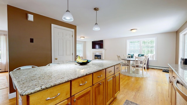3 Marr Farm Way, Scarborough, ME 04074 - kitchen with light wood-style floors, light stone counters, a fireplace, pendant lighting, and brown cabinetry
