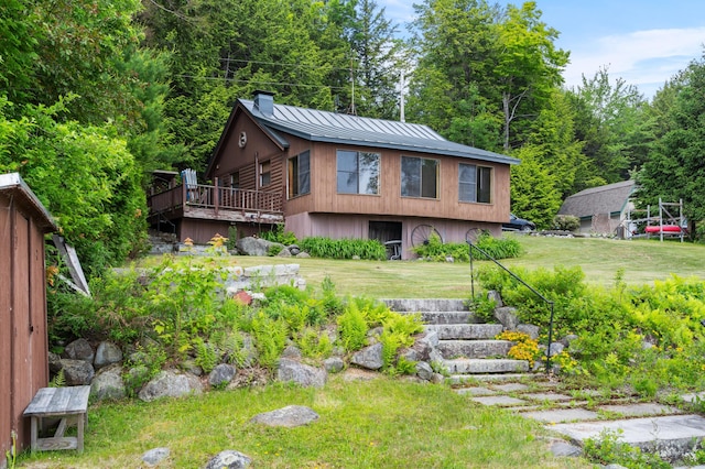 76 Colony Rd, Belgrade, ME 04917 - view of front of house featuring a chimney, a standing seam roof, a metal roof, a wooden deck, and a front yard