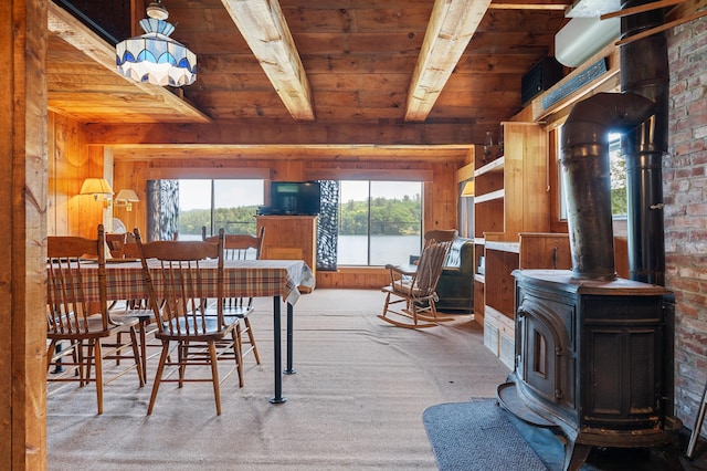 76 Colony Rd, Belgrade, ME 04917 - dining room with a wood stove, a wood ceiling with exposed beams, wood walls, and carpet floors