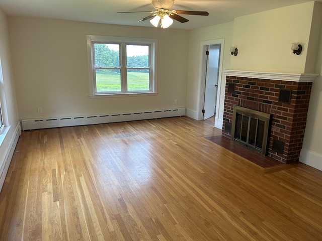 323 Montsweag Rd, Woolwich, ME 04579 - unfurnished living room featuring a baseboard heating unit, wood finished floors, ceiling fan, and a brick fireplace