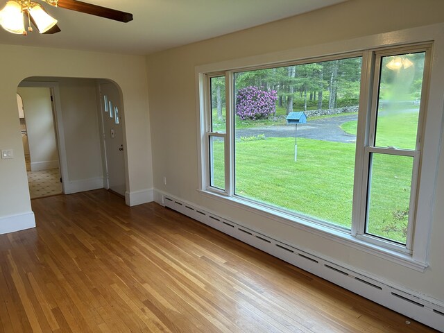 323 Montsweag Rd, Woolwich, ME 04579 - spare room with arched walkways, baseboard heating, light wood-style floors, and a ceiling fan
