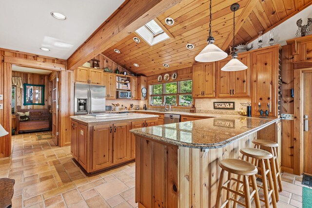 59 Wild Acres Rd, Raymond, ME 04071 - kitchen featuring vaulted ceiling, appliances with stainless steel finishes, a skylight, light stone countertops, and backsplash