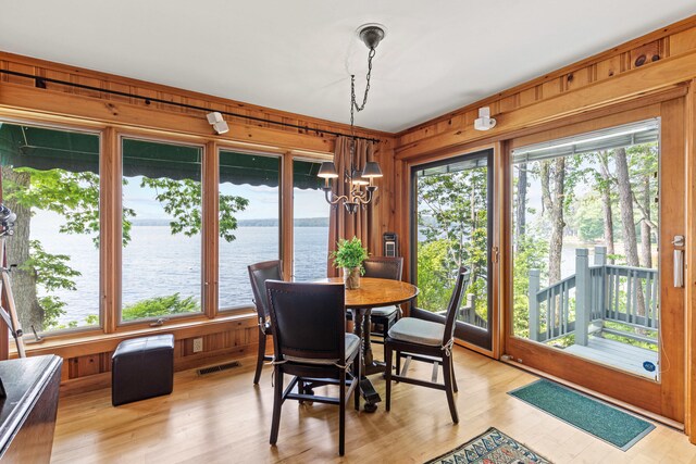59 Wild Acres Rd, Raymond, ME 04071 - dining area with plenty of natural light, a chandelier, wood walls, a water view, and light wood-style flooring