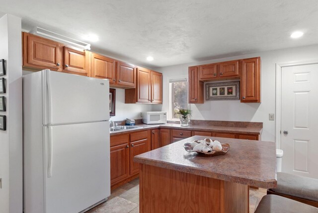 17 White Cap Ln, Wells, ME 04090 - kitchen with white appliances, a center island, recessed lighting, a kitchen breakfast bar, and brown cabinets