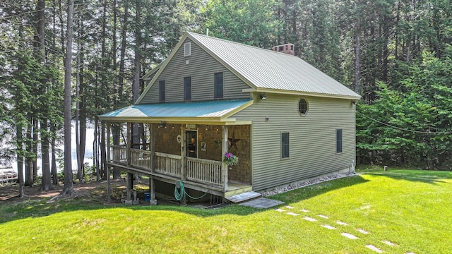 115 Fuller Ln, Denmark, ME 04022 - view of front facade featuring a porch, a chimney, a metal roof, a front lawn, and a forest view