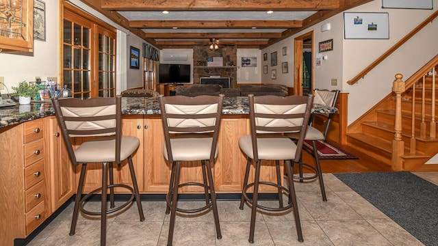 115 Fuller Ln, Denmark, ME 04022 - kitchen with a stone fireplace, a breakfast bar, open floor plan, beam ceiling, and glass insert cabinets