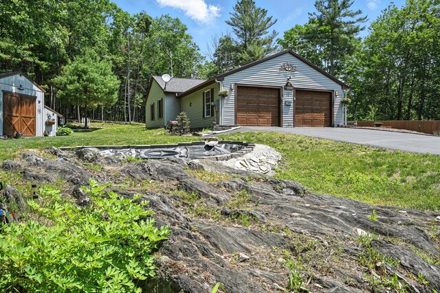 10 Tenacious Way, Augusta, ME 04330 - ranch-style home with a front yard, asphalt driveway, an attached garage, and a shed