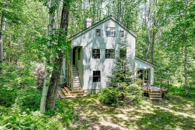 265 Greenacre Rd, Lincolnville, ME 04849 - back of property with a chimney, a wooden deck, a wooded view, and stairway