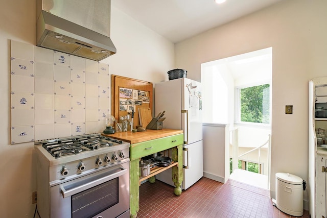 265 Greenacre Rd, Lincolnville, ME 04849 - kitchen with wall chimney range hood, stainless steel range with gas cooktop, freestanding refrigerator, and plenty of natural light