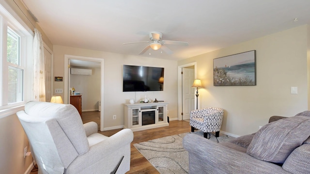 15 Cattail Ln, Monmouth, ME 04259 - living area with ceiling fan, wood finished floors, a wall unit AC, and a glass covered fireplace