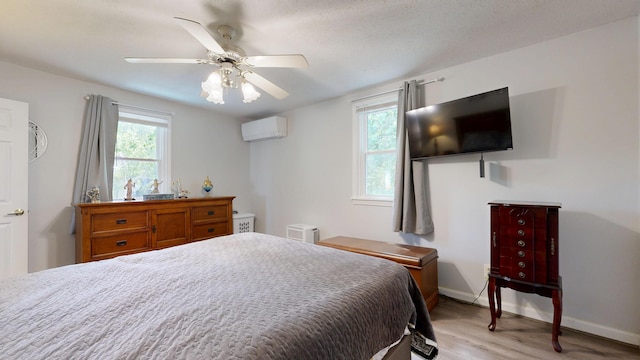 15 Cattail Ln, Monmouth, ME 04259 - bedroom with a wall unit AC, multiple windows, light wood-type flooring, and a ceiling fan