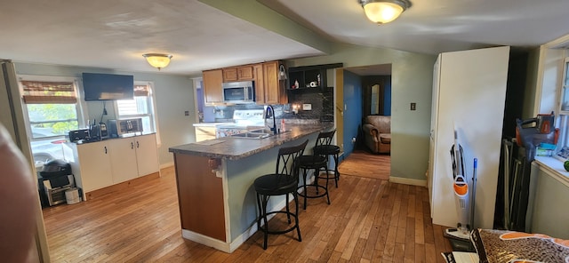 48 Gary St, Paris, ME 04281 - kitchen featuring stainless steel microwave, light wood finished floors, a breakfast bar area, tasteful backsplash, and dark countertops