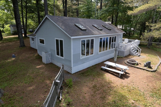 24 Paradise Dr, Monmouth, ME 04259 - back of house with an outdoor fire pit, a wooden deck, roof with shingles, and view of wooded area