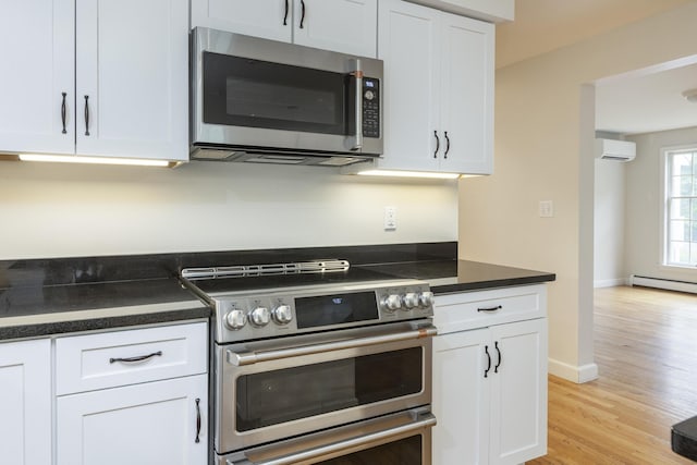 3 Cape Woods Dr Unit 3, Cape Elizabeth, ME 04107 - kitchen featuring stainless steel appliances, a wall mounted AC, dark countertops, white cabinetry, and light wood-type flooring