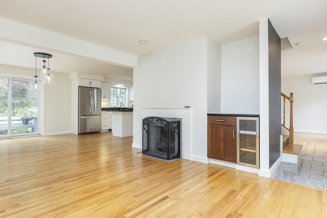 3 Cape Woods Dr Unit 3, Cape Elizabeth, ME 04107 - unfurnished living room featuring beverage cooler, light wood finished floors, stairway, a fireplace, and a wall unit AC