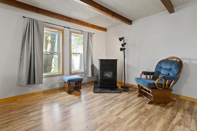 257 N Ave, Skowhegan, ME 04976 - living area featuring a wood stove, beam ceiling, wood finished floors, and a textured ceiling