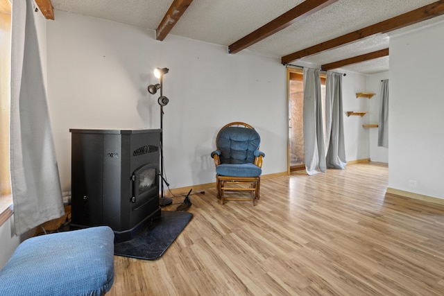 257 N Ave, Skowhegan, ME 04976 - living area featuring a wood stove, beamed ceiling, wood finished floors, and a textured ceiling