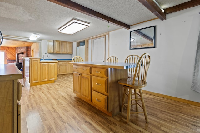 257 N Ave, Skowhegan, ME 04976 - kitchen featuring light wood finished floors, a textured ceiling, a breakfast bar area, a center island, and beamed ceiling