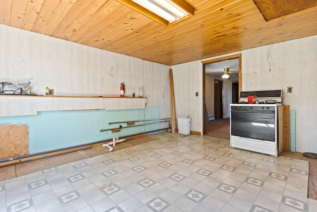 257 N Ave, Skowhegan, ME 04976 - kitchen with white gas range oven, a ceiling fan, tile patterned floors, wooden ceiling, and wood walls