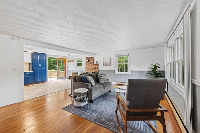 267 Manchester Rd, Standish, ME 04085 - living room featuring a baseboard radiator, light wood finished floors, healthy amount of natural light, and a fireplace