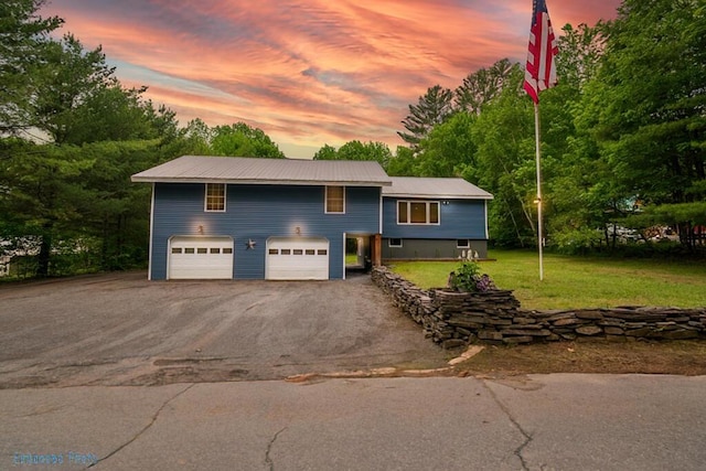 44 Donigan Rd, Moscow, ME 04920 - view of front of home with asphalt driveway, a garage, a front lawn, and a metal roof