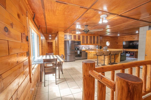 44 Donigan Rd, Moscow, ME 04920 - kitchen with stainless steel appliances, a ceiling fan, wooden walls, light tile patterned flooring, and light countertops