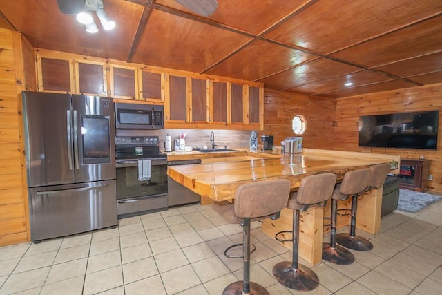 44 Donigan Rd, Moscow, ME 04920 - kitchen featuring stainless steel appliances, light tile patterned flooring, butcher block countertops, wood walls, and a kitchen bar