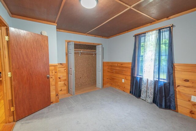 44 Donigan Rd, Moscow, ME 04920 - unfurnished bedroom featuring a wainscoted wall, carpet flooring, wood walls, and a closet