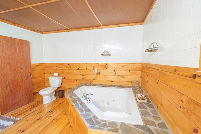 44 Donigan Rd, Moscow, ME 04920 - full bathroom featuring a tub with jets, wooden walls, and wood finished floors