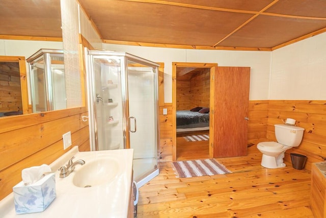 44 Donigan Rd, Moscow, ME 04920 - ensuite bathroom featuring wood-type flooring, a stall shower, vanity, wood walls, and wainscoting