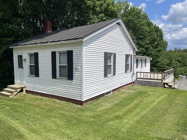 406 Cushman Rd, Winslow, ME 04901 - view of side of home featuring a deck, a metal roof, a standing seam roof, a lawn, and a chimney
