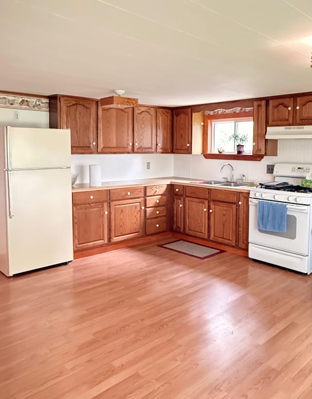 1190 Indian River Rd, Addison, ME 04606 - kitchen with white appliances, under cabinet range hood, brown cabinetry, and light wood-style floors