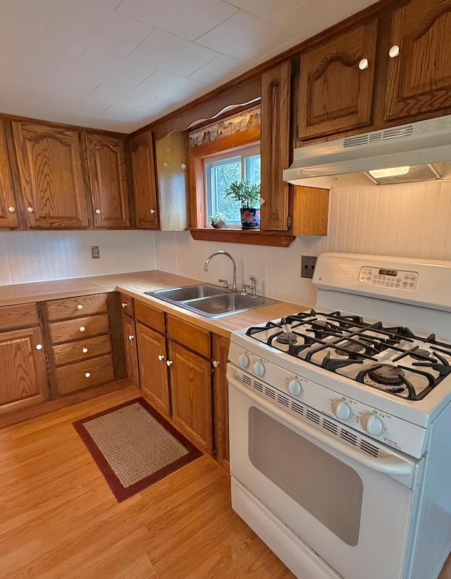 1190 Indian River Rd, Addison, ME 04606 - kitchen featuring white gas range, range hood, brown cabinets, light wood-style flooring, and light countertops